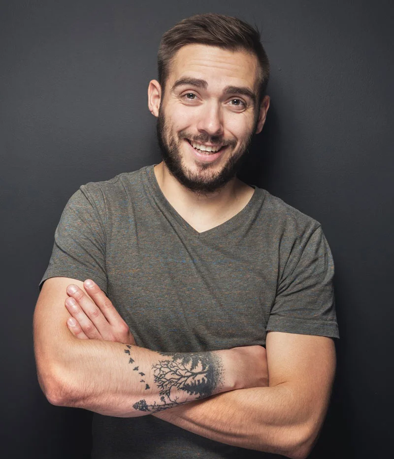 Male with tattoos leaning against a wall